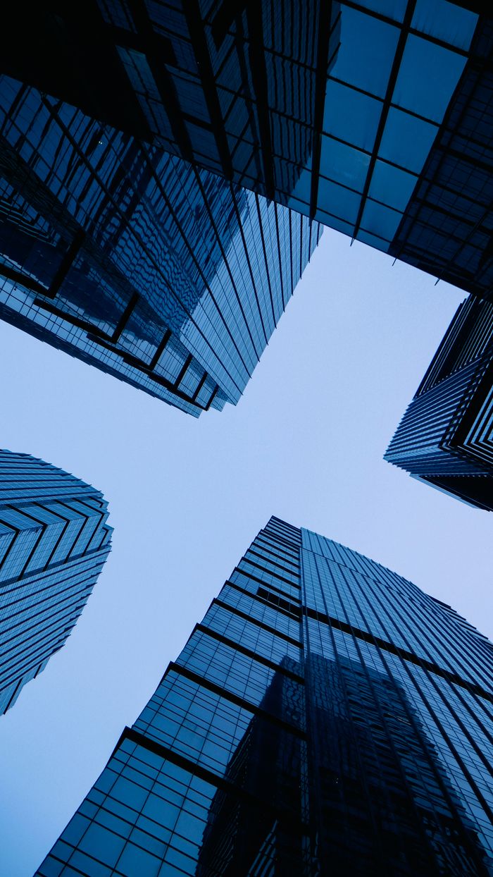 Low angle view of sleek, modern skyscrapers with glass facades forming geometric pattern against the sky.